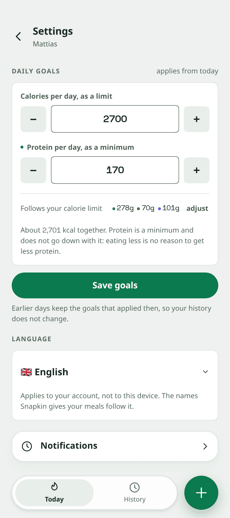 A tela de ajustes do Snapkin. Metas diárias de 2.700 calorias como limite e 170 gramas de proteína como mínimo. Embaixo, um seletor de idioma em inglês, com uma nota. Ela diz que o idioma é da sua conta e não deste aparelho, e que os nomes que o Snapkin dá às suas refeições acompanham.